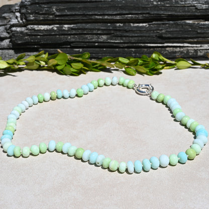 A beaded necklace made of pastel light blue, mint green, and pale yellow-green round beads, with a silver clasp. 