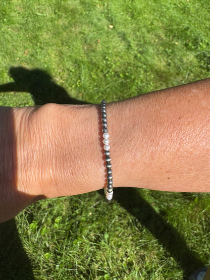 A beaded bracelet with black and white beads worn on a person's wrist, photographed outdoors on a grassy lawn.